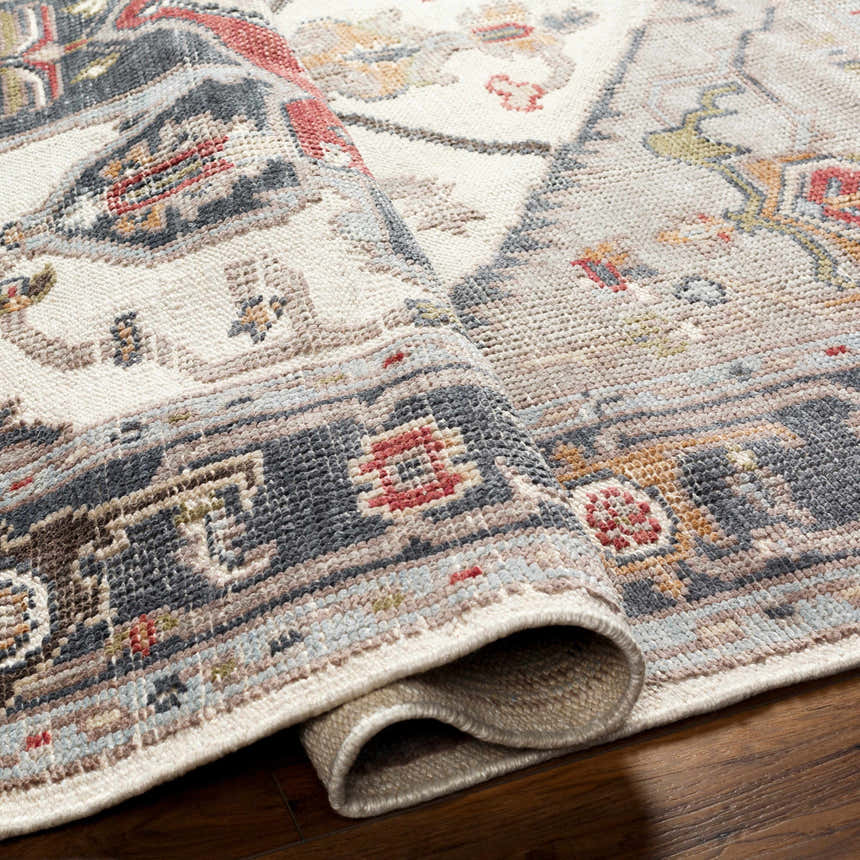 Close-up of the Halayhayin Premium Rug showing its hand-knotted construction, brick red, cream, and gray colors. Fold