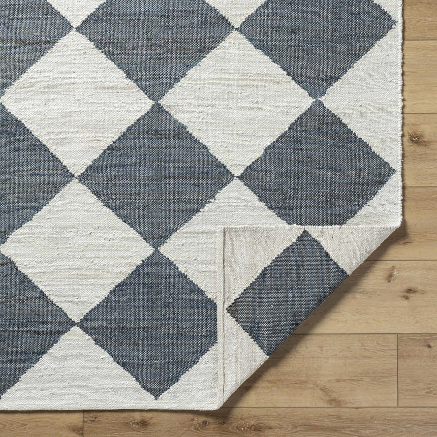 Close-up of Antho Handmade Vivir x LIVABLISS VVAT-2302 area rug with slate gray and ivory diamond pattern on wood floor. Fold