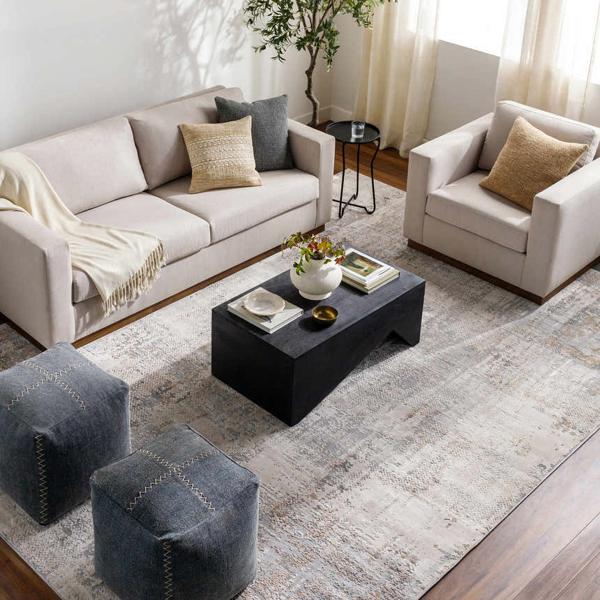 Living room scene with a neutral sofa, chair, and Ironwood Textured Luxe Rug in charcoal, gray, and brown tones. Roomscene-Rectangle