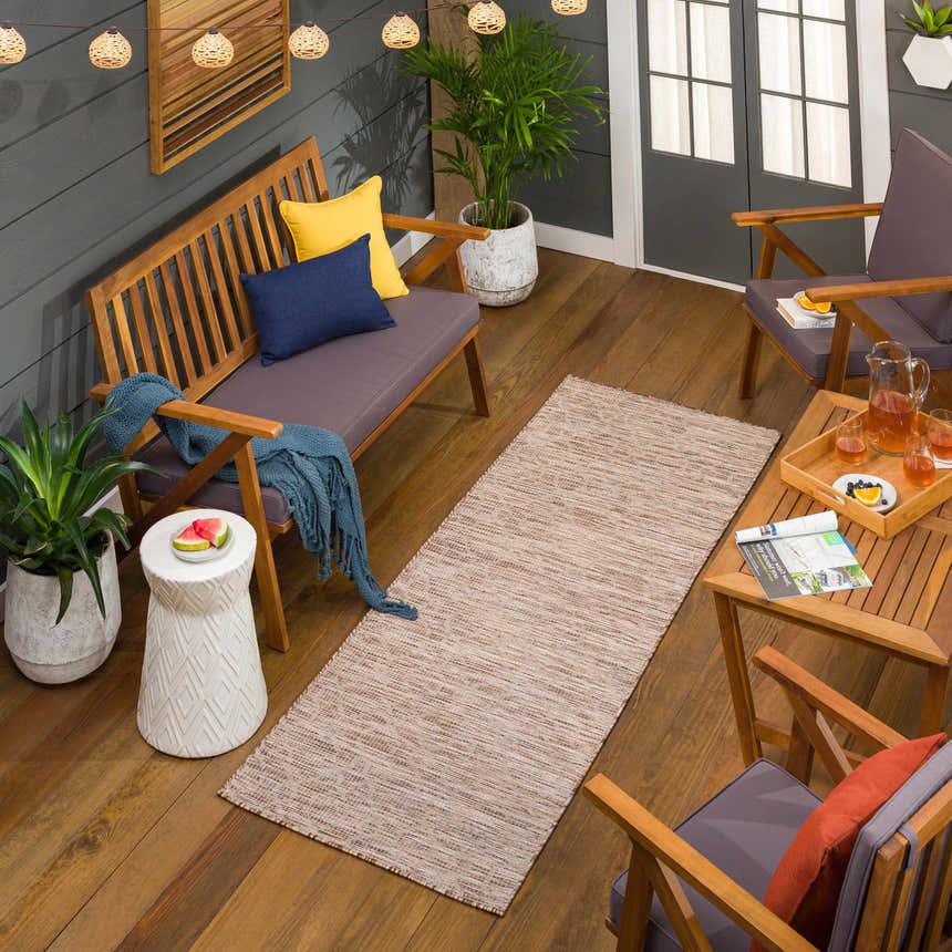 Cozy patio scene with Jerramungup Flatweave runner rug, wood furniture, string lights, and potted plants. Brown, cream, and tan tones. Roomscene-Runner