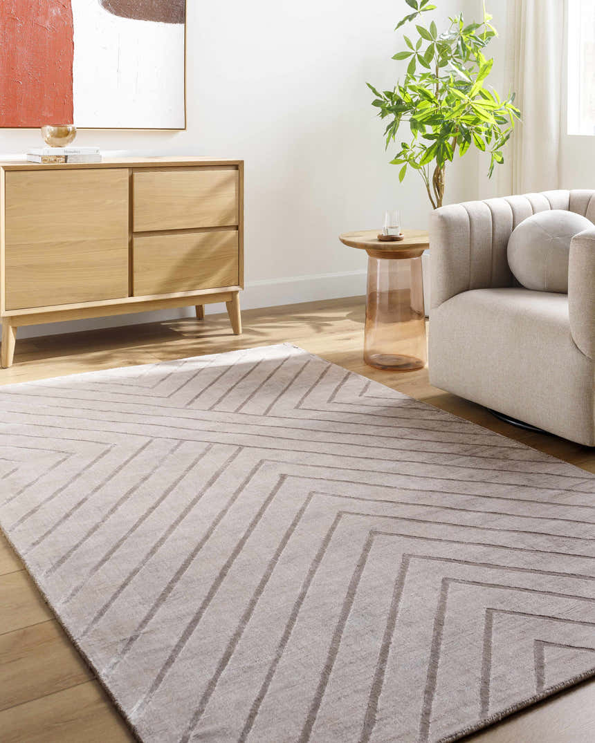 Living room scene with a Tavran Taupe rug, light wood floors, beige armchair, and cabinet with modern art. Roomscene-Rectangle
