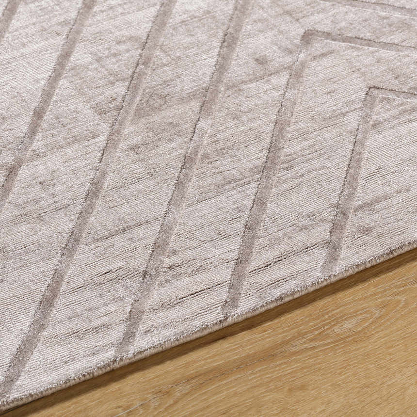 Close-up of the Tavran Taupe rug showing subtle linear texture and soft beige tones on a wood floor. Viscose hand-loomed rug. Texture