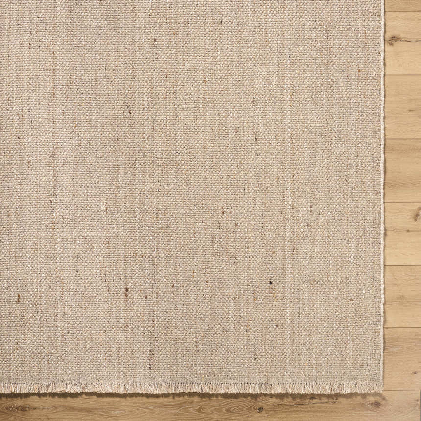 Close-up of the hand woven texture of the Cilaa Modern Wool Area Rug in a neutral beige color on hardwood floor. Corner