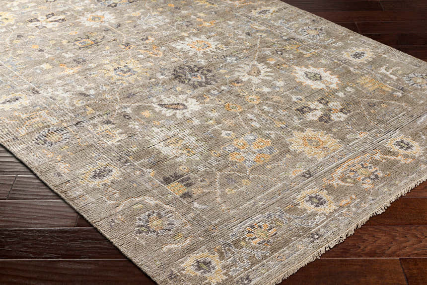 Close-up of the Kajiado Area Rug showing its charcoal, cream, and coral floral pattern and hand-knotted texture. Corner