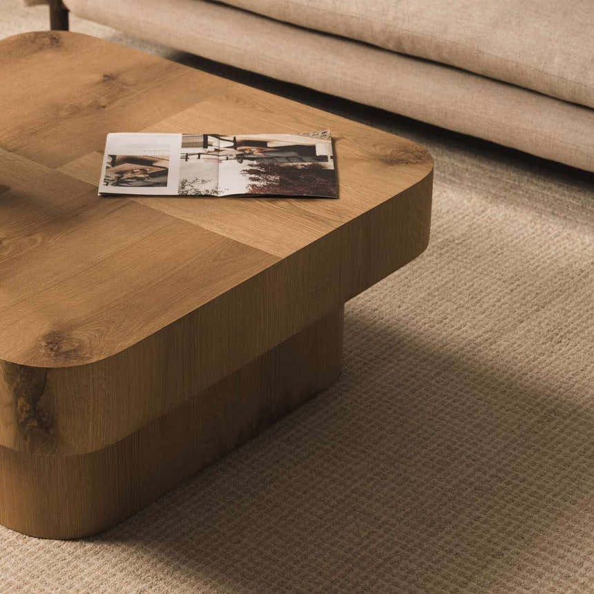 Close-up of the textured, ivory Kayoko Area Rug under a wood coffee table and neutral sofa. Roomscene-Rectangle