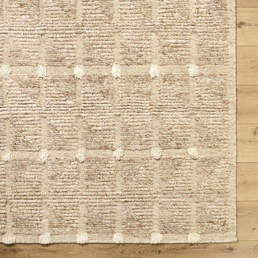 Close-up of the hand woven Keegan Area Rug. Beige, sandstone, and taupe wool rug with a textured, geometric pattern. Corner