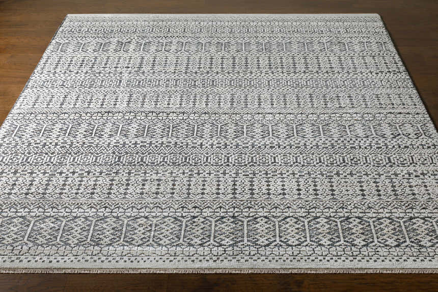 Close-up of the Kiara Area Rug, a hand-knotted wool rug with a bohemian-inspired geometric pattern in black, charcoal, and light gray. Front