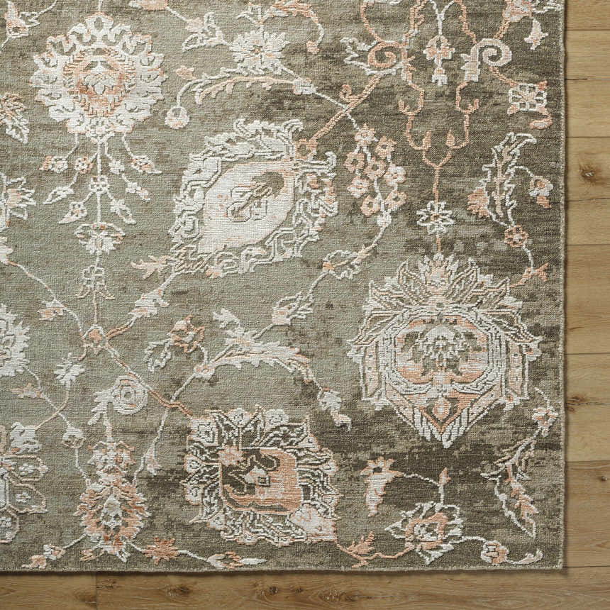 Close-up of the Limay Premium Wool Rug. Hand-knotted rug with a traditional floral pattern in olive, beige, and coral tones. Corner
