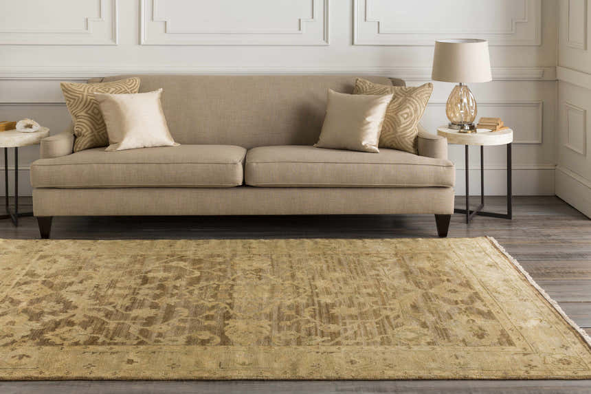 Living room scene with a tan sofa and the Lochmaben Premium Wool Rug in light brown and tan colors on a dark wood floor. Roomscene-Rectangle