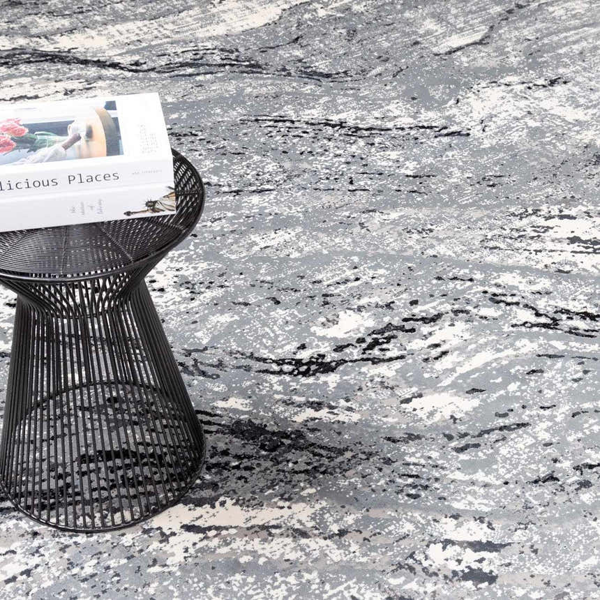 Close-up of the Littleport Luxury Fringed Faux Silk Rug. Abstract pattern in black, charcoal, gray, and light gray. Styleshot