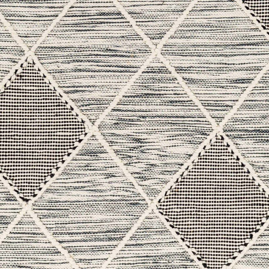 Close up of the Mabua Tasseled Jute&Wool Rug showing black and cream geometric diamond pattern, hand woven texture. Swatch