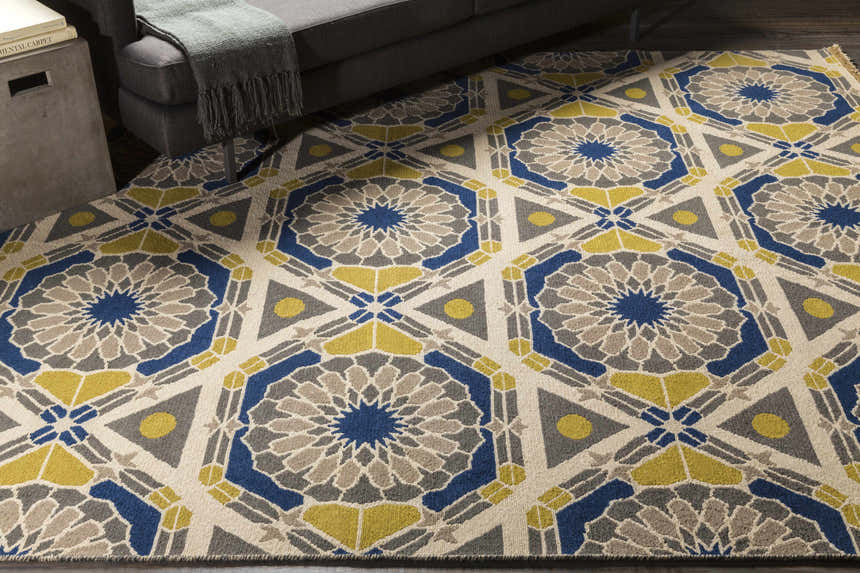 Living room scene with the Mesena Area Rug, featuring an ivory, navy, and tan geometric pattern. Styleshot