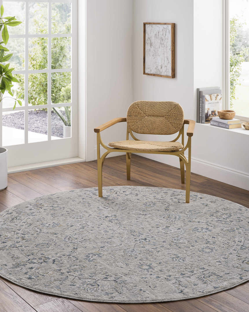Light-filled room with round Melianna Gray Blue rug under a woven chair. Farmhouse style with wood floors. Roomscene-Round