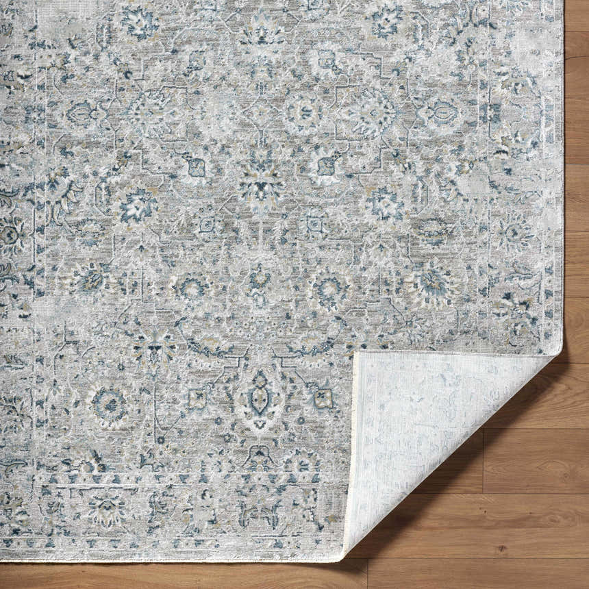 Close-up of the Melianna Gray Blue Luxe rug showing its traditional floral pattern and soft texture on a wood floor. Fold