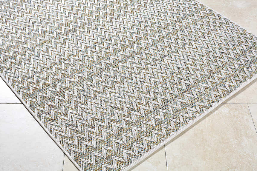 Close-up of the Alazne Ivory Area Rug. Features a textured, geometric chevron pattern in ivory, sage, tan, and taupe. Corner