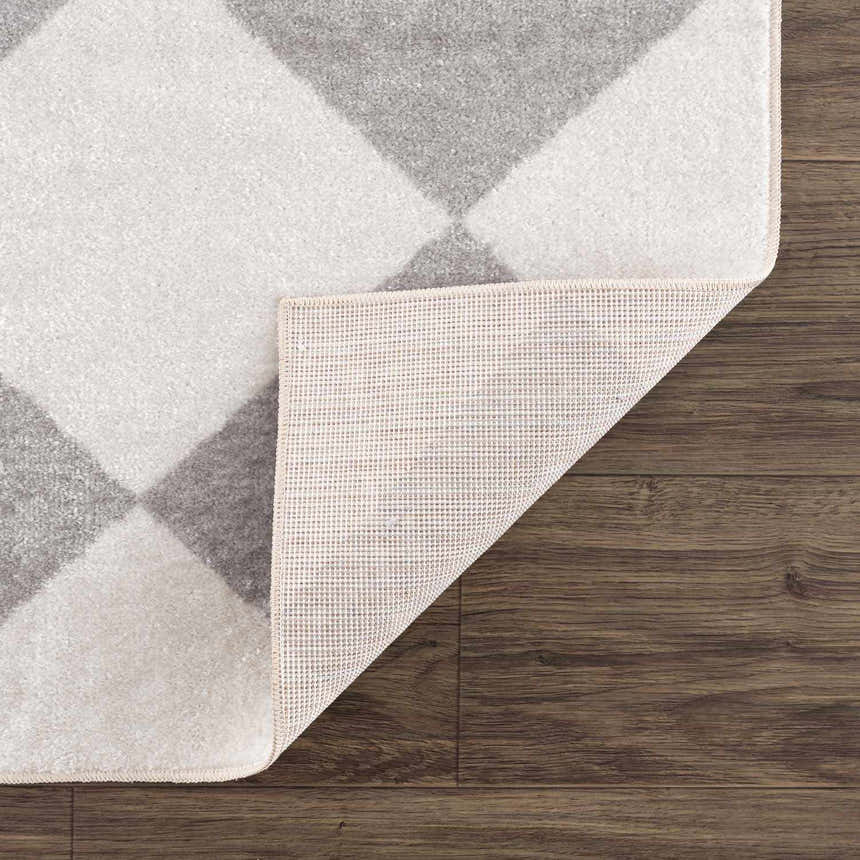 Close up of Ulric Light Gray Diamond Washable Area Rug showing the cream and gray diamond pattern and rug backing. Fold