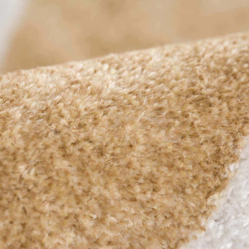 Close-up of the soft, textured pile of the Ulric Light Brown Diamond Washable Area Rug. Cream and light brown tones. Fold