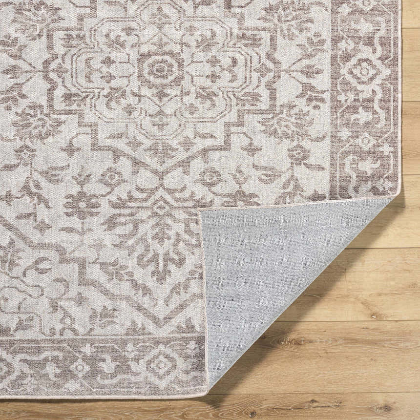 Close-up of the Ansgar Washable Wool Area Rug. Beige, ivory, and taupe floral pattern. Hand-woven texture. Fold
