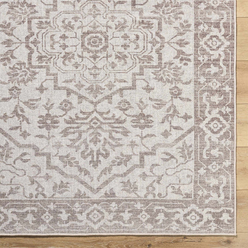 Close-up of the beige and taupe Ansgar Washable Wool Area Rug, featuring a traditional floral pattern and hand-woven texture. Corner