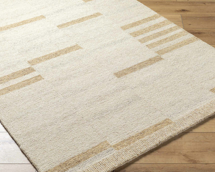 Close-up of the hand-tufted Nadav Beige Area Rug, a wool rug with a geometric tan and ivory design on wood flooring. Corner