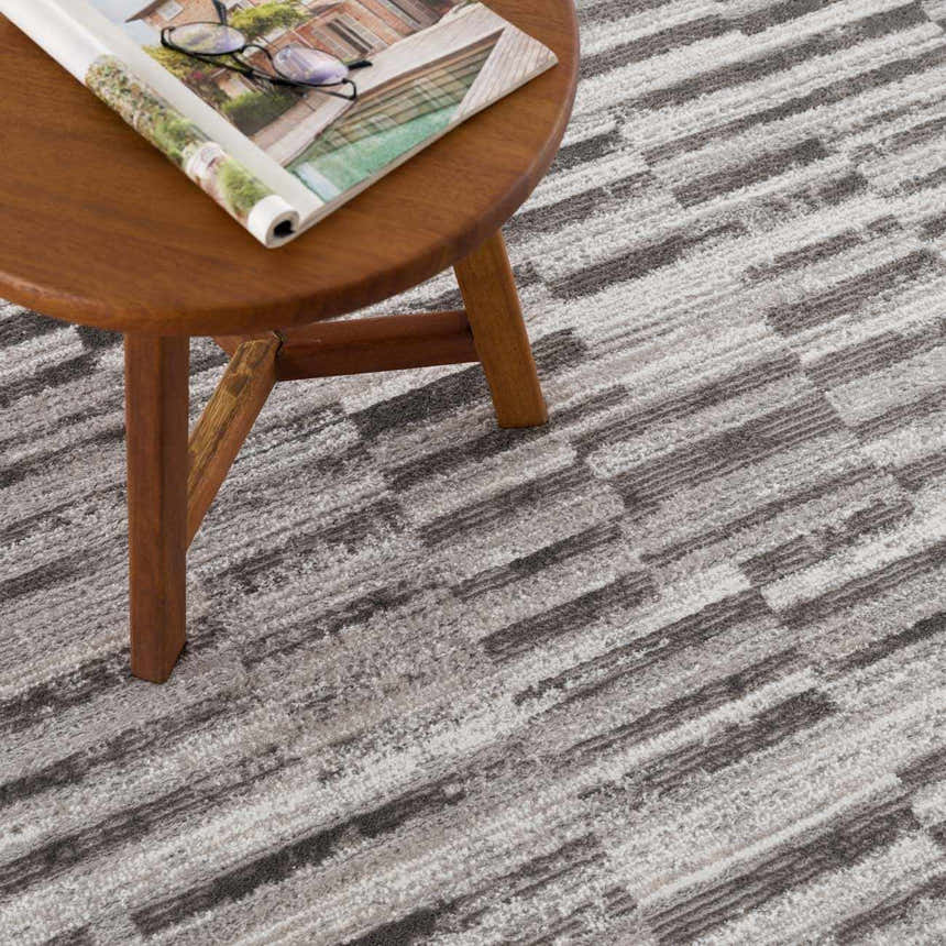 Close-up of the Arissa Broken-Striped Area Rug in gray, black, and white with a geometric pattern and soft texture. Styleshot