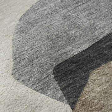 Close-up of the Dalyn Luxury Odyssey OY17 Taupe Washable Area Rug. Features taupe, ivory, and dark brown geometric shapes.
