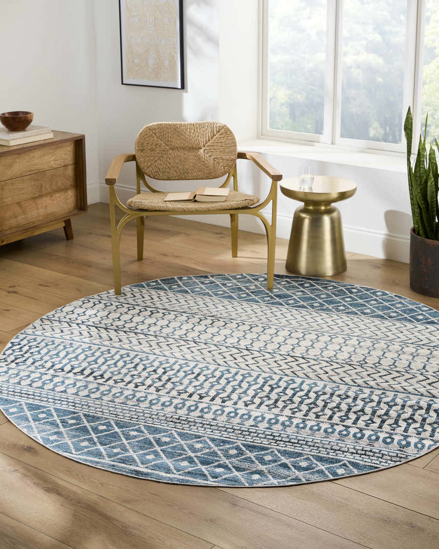 Sunlit room with round Pinamopoan Washable Area Rug in blue and beige, a woven chair, and wood accents. Roomscene-Round