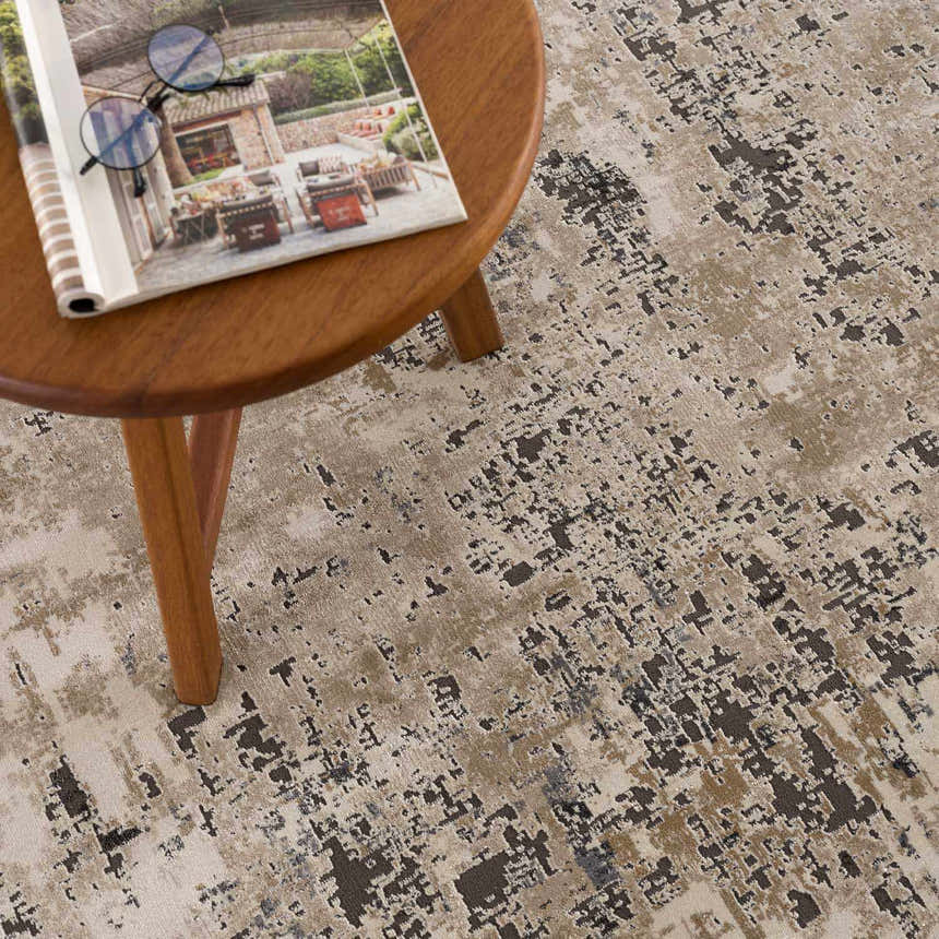 Close-up of the Pewamo Area Rug in black, charcoal, beige, and tan with a contemporary abstract design. Styleshot