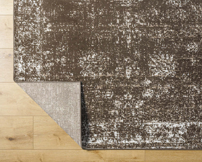 Close-up of the Quita Area Rug showing a brown and ivory farmhouse pattern and the rug's backing. Fold