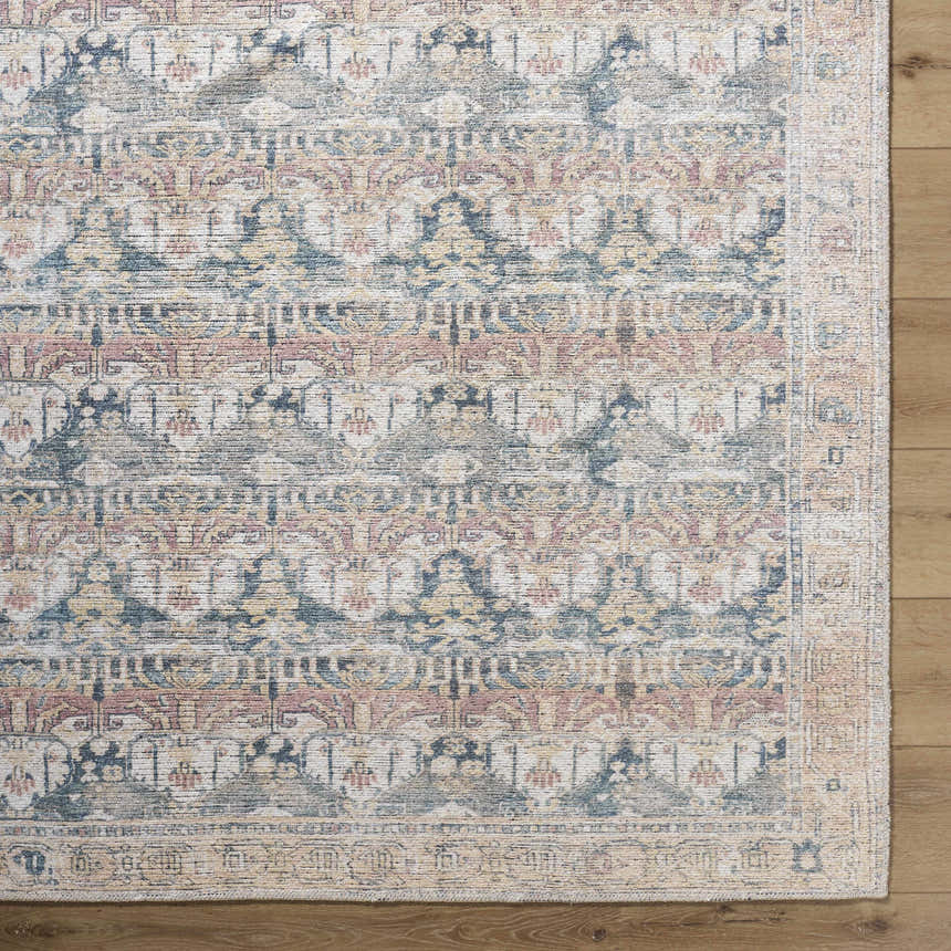 Close-up of the Arushi Washable Area Rug. Farmhouse style rug with cream, green, orange, rust, and tan colors. Corner