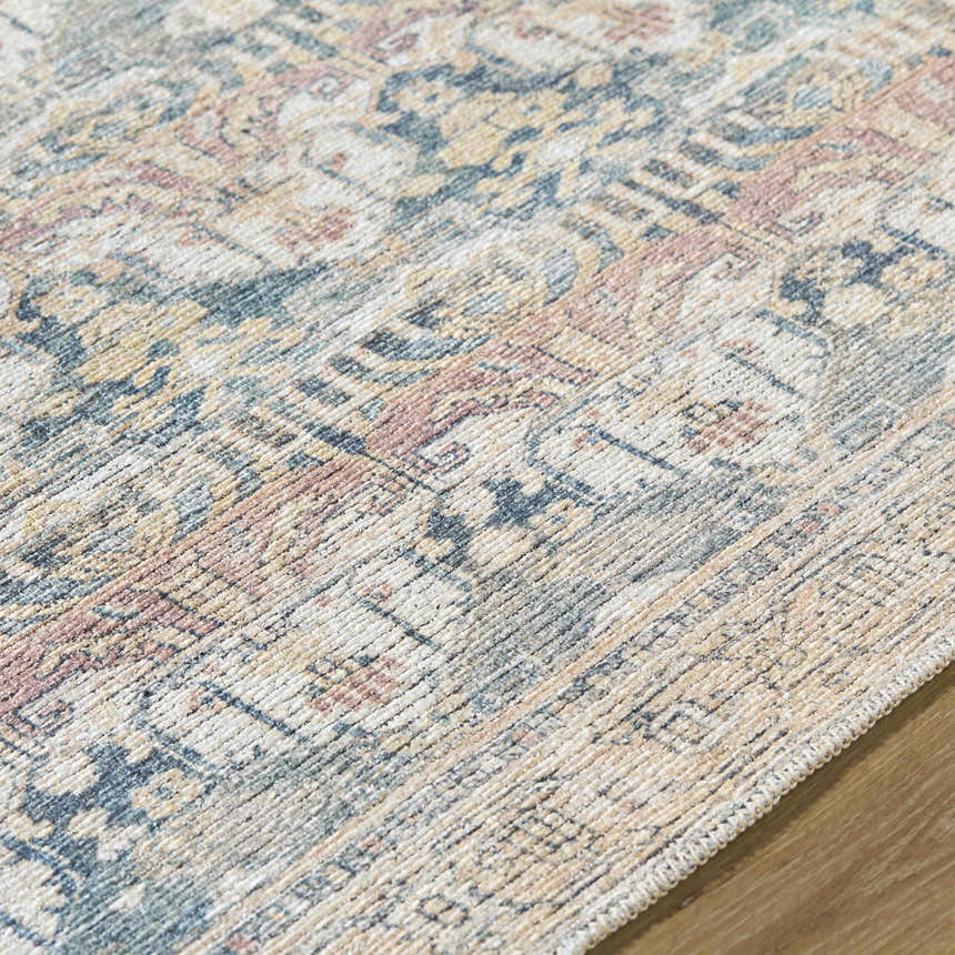 Close-up of the Arushi Washable Area Rug, featuring a traditional pattern in cream, green, orange, rust, and tan. Texture