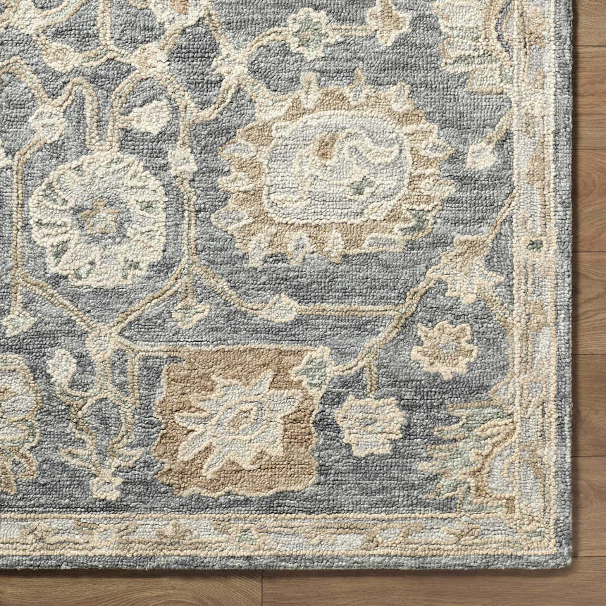 Close up of the hand tufted Auryon Oushak Wool Area Rug. Slate blue rug with off white and tan floral pattern. Corner
