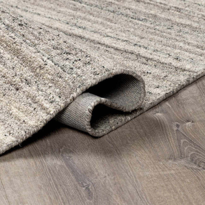 Close-up of the hand-tufted Capote Stone Gray Area Rug showing its wool texture, gray tones, and durable backing. Fold