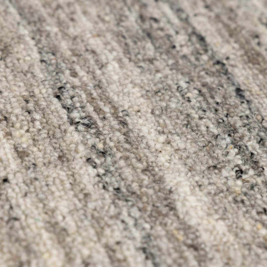 Close-up of the hand-tufted Capote Stone Gray Area Rug. Wool texture in ash, charcoal, ivory, and stone gray. Texture