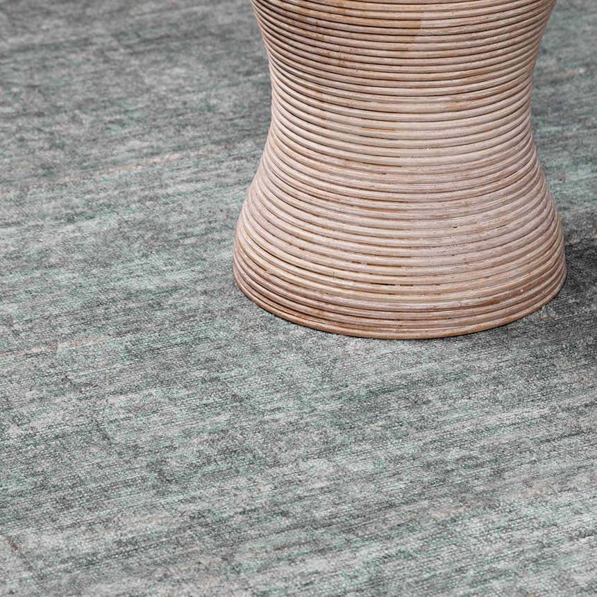 Close-up of Livabliss x Galey Alix Maria Elena II rug in gray with a subtle vintage medallion pattern and a round rattan table. Styleshot