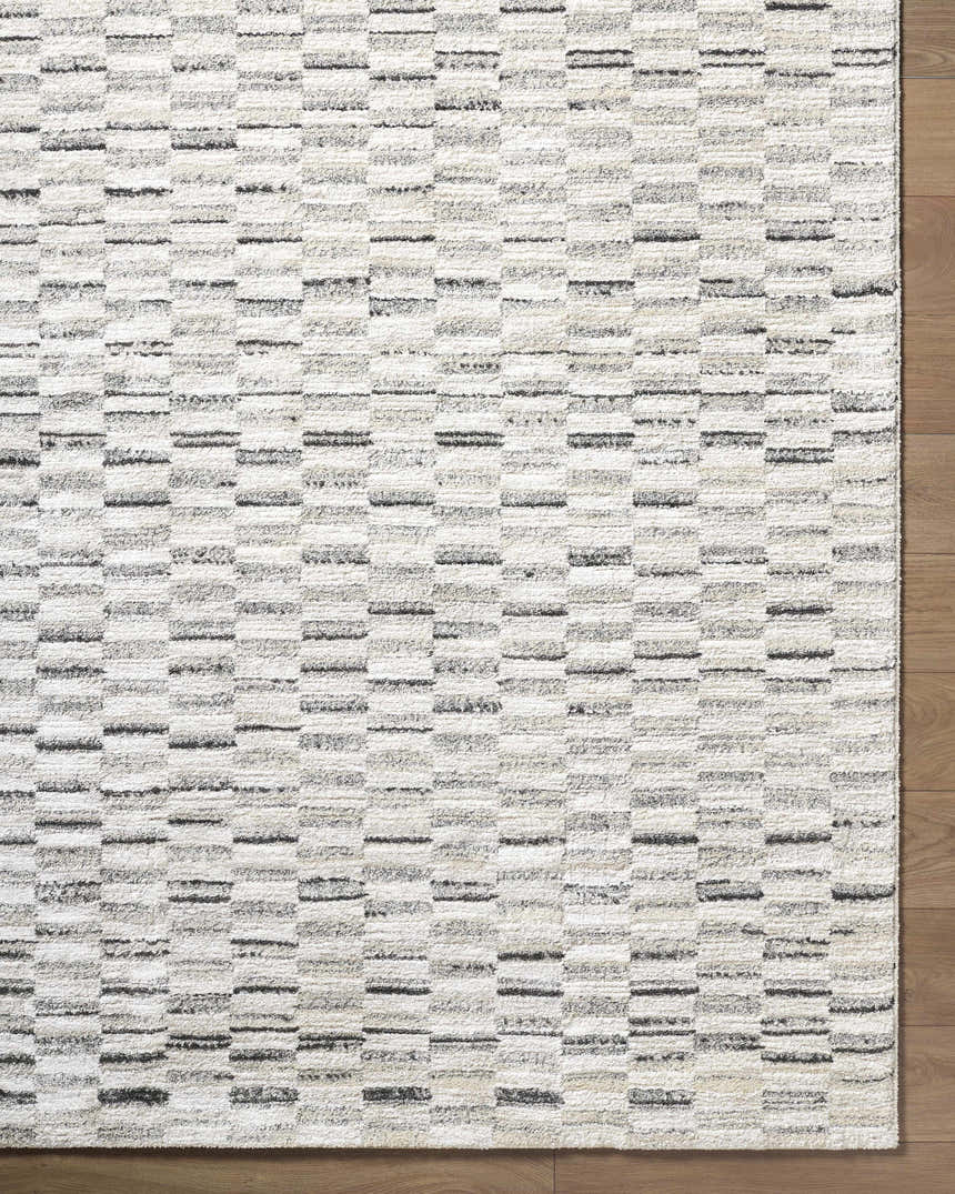 Close-up of the Reece Luxe Rug. Beige, cream, and black horizontal stripes create a contemporary pattern. Corner