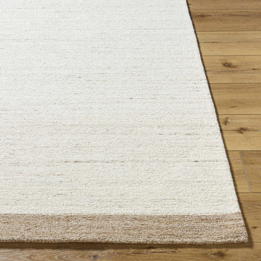 Close-up of the hand-tufted Amabel Area Rug showing its ivory, beige, and tan colors and wool texture on wood floor. Front