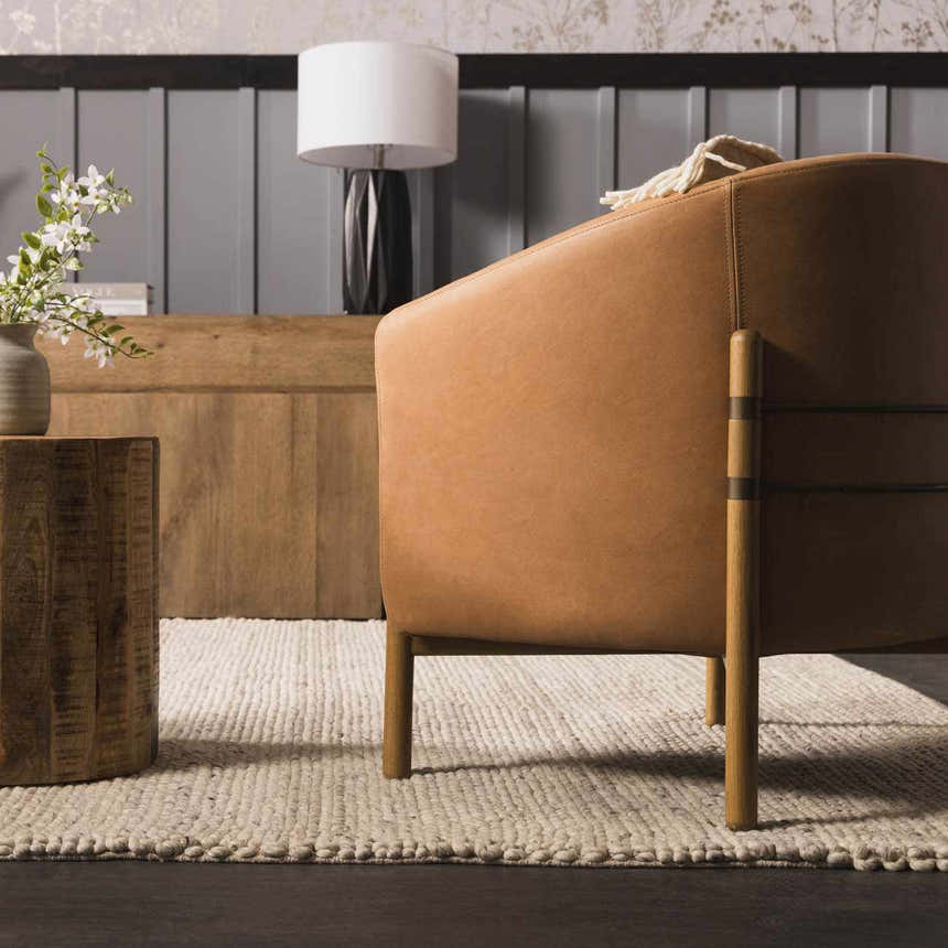 Living room scene with a tan leather chair on a cream Salvo Luxury Hand Woven Wool Area Rug. Styleshot
