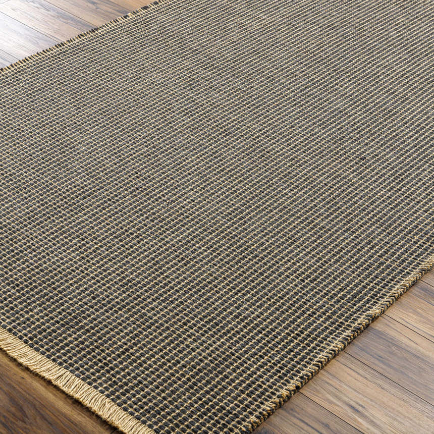 Close-up of the Kimi Machine Woven Becki Owens x LIVABLISS rug. Black and light brown jute with a textured, grid-like design. Corner