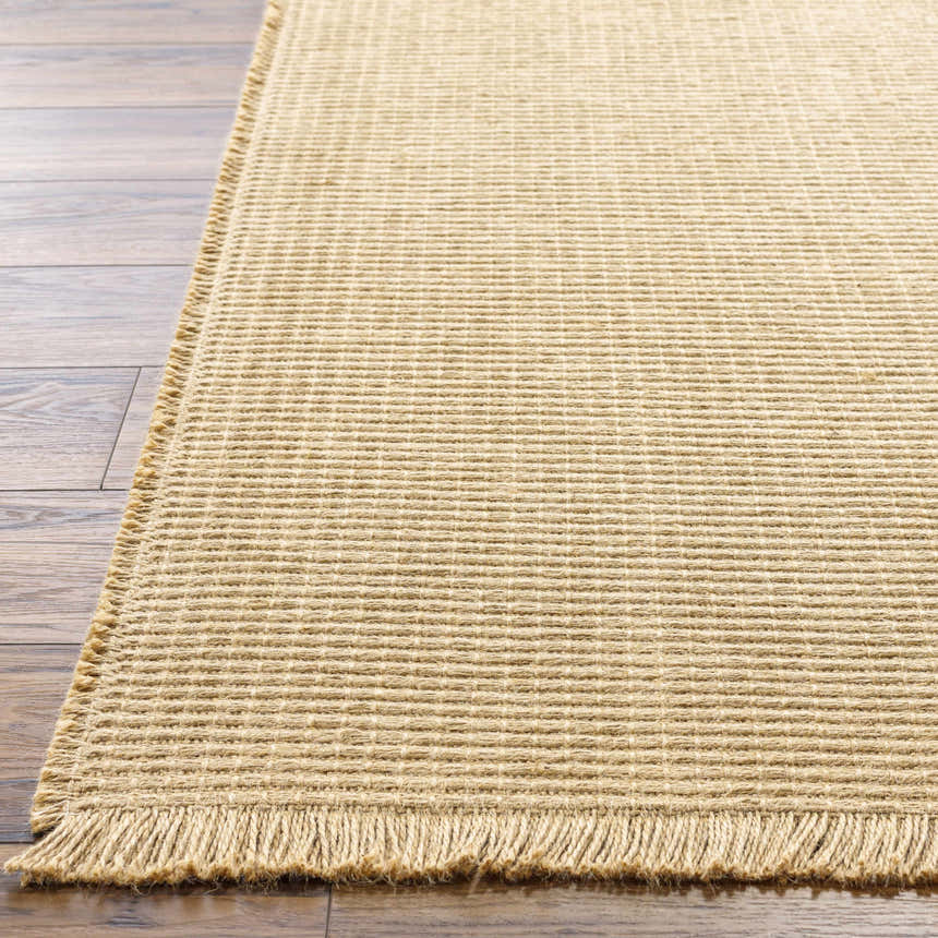 Close-up of the light brown Kimi Machine Woven Becki Owens x LIVABLISS area rug showing jute texture and fringe detail. Front