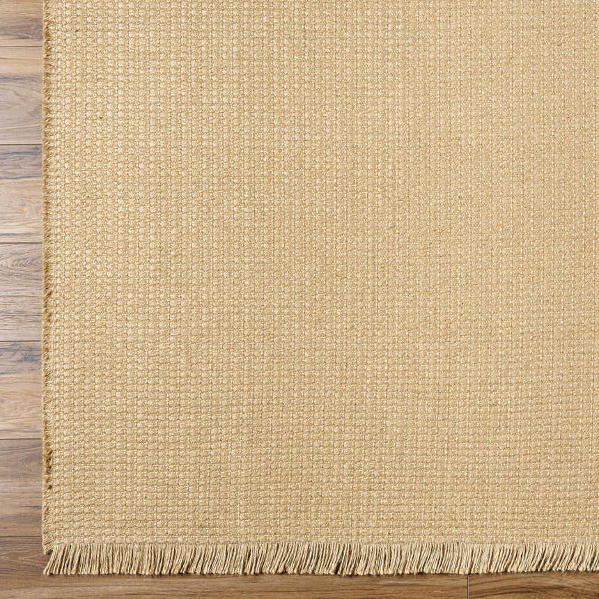 Close-up of the light brown Kimi Machine Woven Becki Owens x LIVABLISS rug showing jute texture and fringe detail. Corner