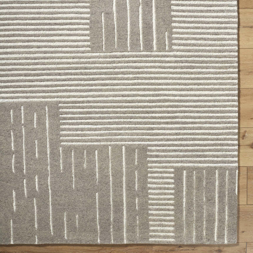 Close-up of Akuji Area Rug. Gray wool rug with a contemporary pattern of white stripes and rectangles on wood floor. Corner