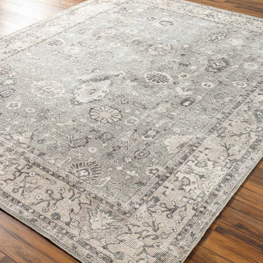Close-up of the Davina Becki Owens x LIVABLISS BOCC-2301 Area Rug. Machine-woven polyester rug in charcoal, gray, taupe, and white floral pattern. Corner