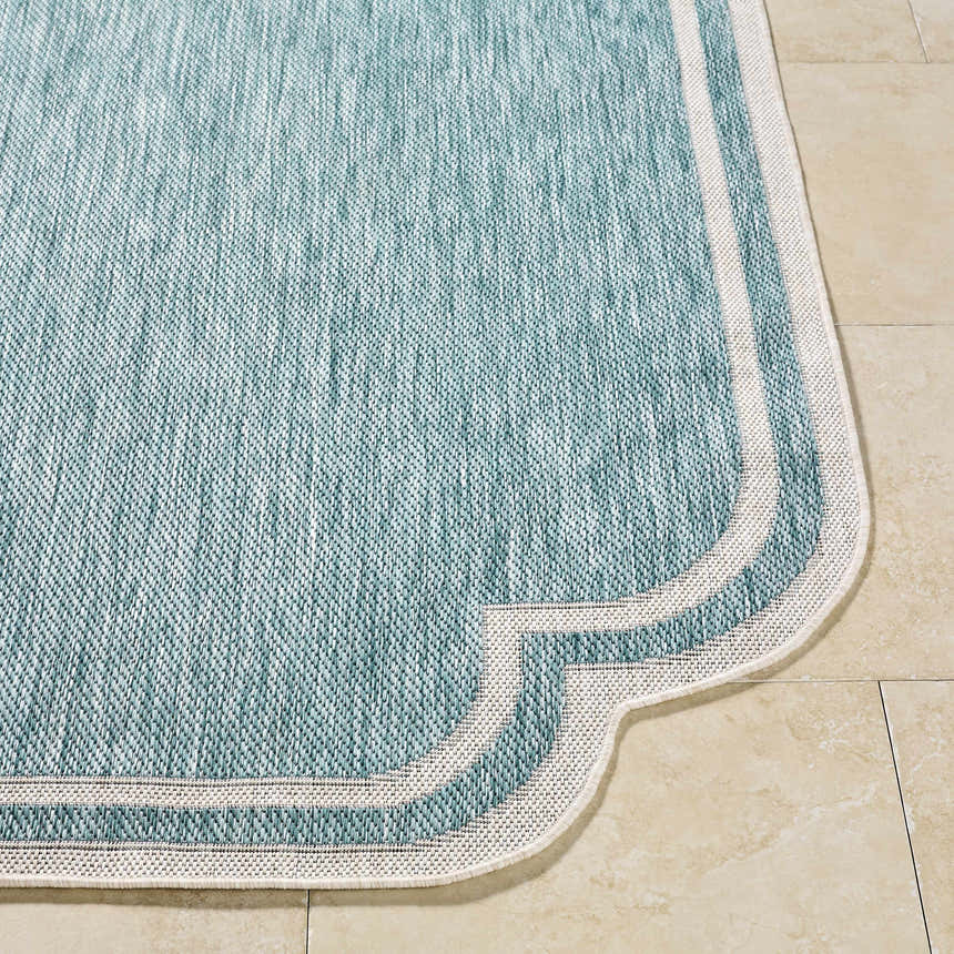 Close-up of Arnola Light Blue Outdoor Rug showing aqua color, cream border, and machine woven texture. Front