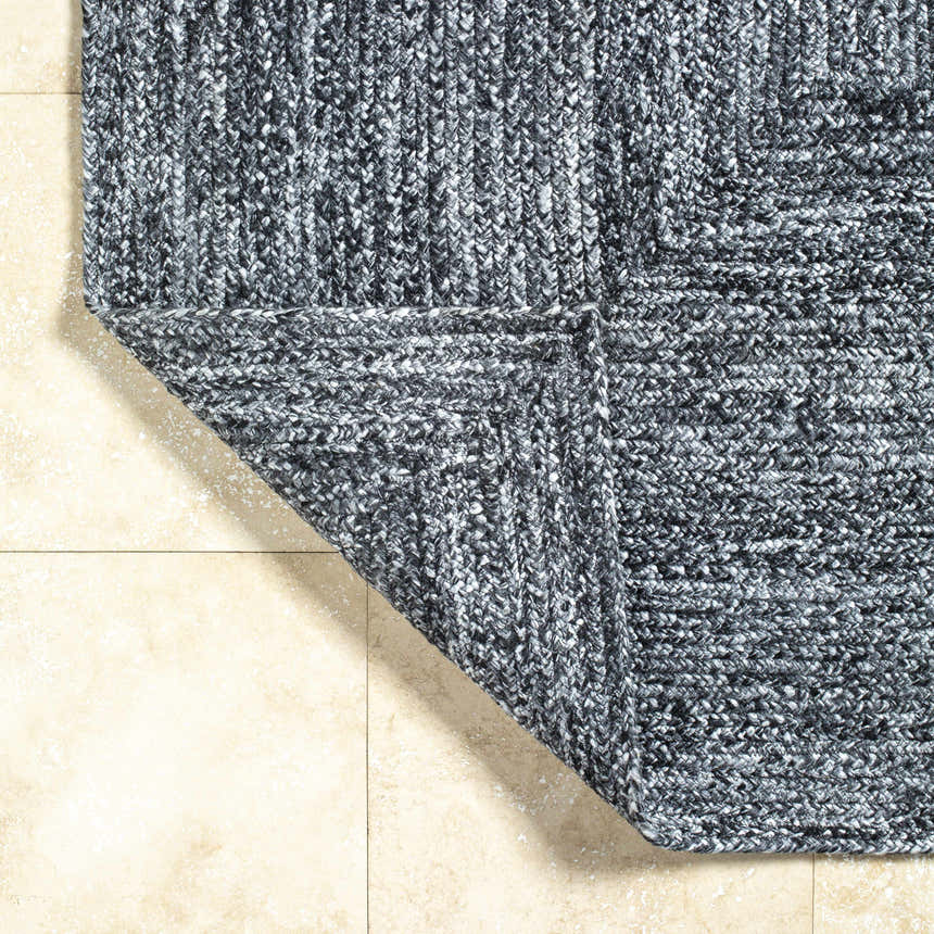Close-up of the hand-woven Kenyi Black Area Rug showing black and white recycled PET yarn texture and corner detail. Fold