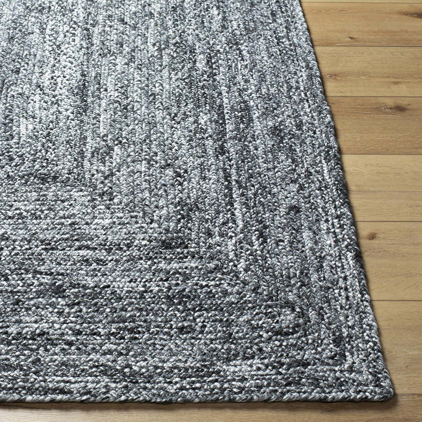 Close-up of the hand woven Kenyi Black Area Rug showing its texture and black and white color on a wood floor. Front