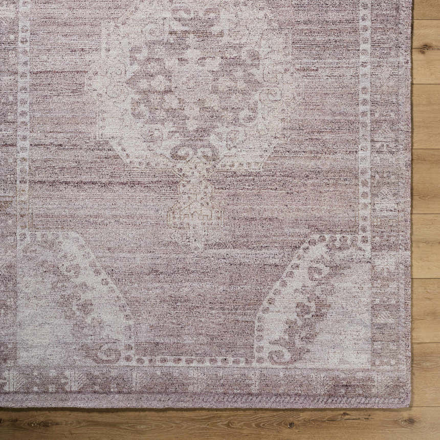 Close-up of the Alafin Area Rug. Hand-tufted polyester rug in blush, cream, dusty rose, and mauve with a traditional design. Corner