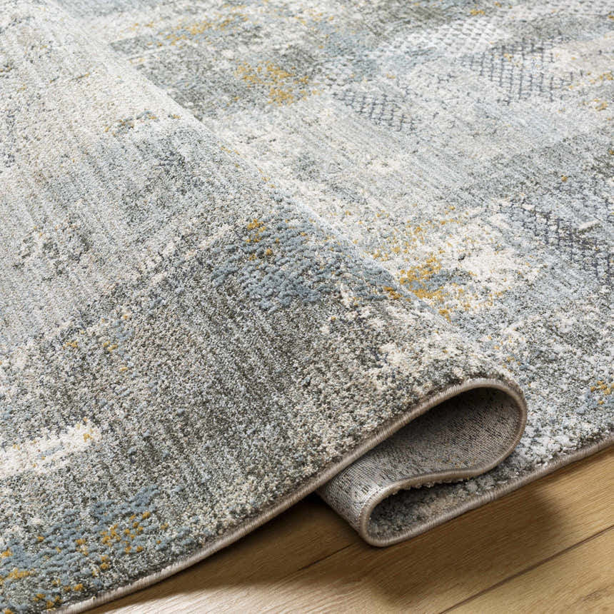 Close-up of the Elina Textured Abstract Rug. The rug has a textured design with dusty sage, ink blue, and mustard accents. Fold