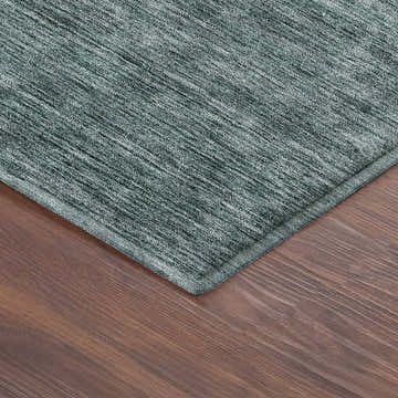 Close-up of the textured Dalyn Luxury Soft Essentials Teal Washable Area Rug on a wood floor.