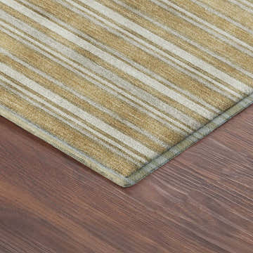 Close-up of the gold striped Dalyn Luxury Soft Essentials area rug on a wood floor.